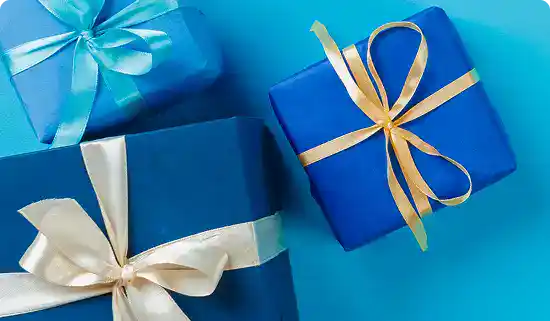 Geschenkboxen in Blau mit goldenen und weißen Schleifen, perfekt für besondere Anlässe.